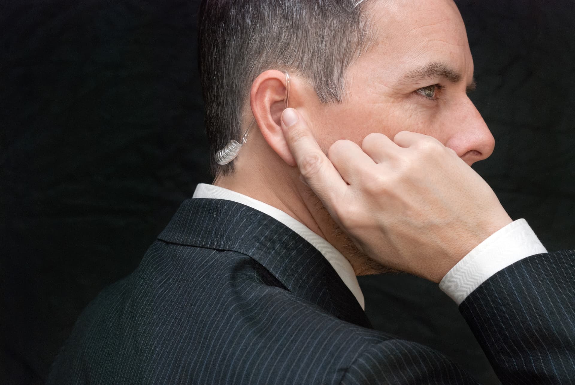 Close protection detail — earpiece and pinstripe suit